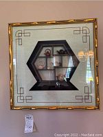 Shadow box with hexagonal shelf containing miniature Asian teapots in ceramic and metal, gold bamboo style framing