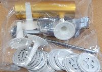 Top view of the 29 piece cookie press set in a clear plastic bag showing metal cookie disks, white plastic handles, and gold colored tool