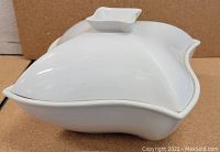White ceramic Godinger Pinwheel lidded dish viewed from the top showing smooth curved edges and integrated lid handle meeting the warmer base.