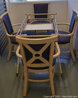 Photo of four lightweight metal chairs placed around the metal dining table frame showing design details of chair backs and frame.