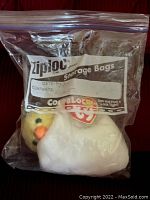 Ty Beanie Baby Eggbert plush toy inside a clear plastic Ziploc storage bag, showing its intact heart-shaped Ty tag and yellow chick face with orange beak.