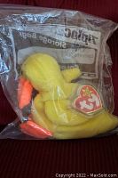 Yellow Ty Beanie Baby Quackers duck plush with orange beak and feet in clear Ziploc storage bag, visible heart-shaped Ty tag intact.