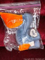 Blue pelican Beanie Baby with orange wings and feet, inside a clear plastic bag showing original tags and labels