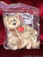 Ty Beanie Baby Signature teddy bear inside a sealed plastic bag, showing plush bear and red Ty heart tag.
