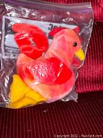 Ty Beanie Baby 'Strut' rooster plush in red, pink, and yellow colors sealed inside a Ziploc storage bag.
