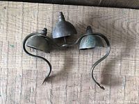 Three metal bells with curved arms forming the door ringer, showing patina and some tarnish.