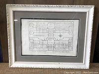 Front view of the framed floor plan print showing the architectural plan detailed in French inside a white ornate frame.