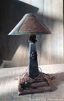 Full view of metal table lamp with faux mica shade attached, showing the floral details on the support and the square base.