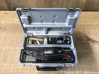 Open case showing Dremel rotary tool and multiple grinding and polishing accessories organized in compartments.