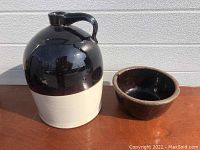 Photo showing both the finger jug and the small redware bowl together on a wooden surface with a white background.