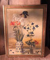 Front view of the gilded wood panel with painted floral image showing two vases with tulips, bellflowers, and other blossoms, bordered with gilded wood Florentine frame.