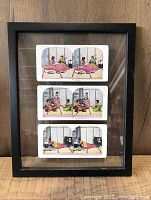 Full view of the black frame with three Japanese stereograph cards mounted inside, each showing pairs of women in traditional settings.