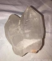 Clear quartz crystal, well-formed with pointed crystals, showing white mineral deposits at base.