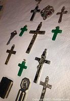 Photo shows 13 religious items including crosses, crucifixes, and a mini Bible arranged on a white cloth.