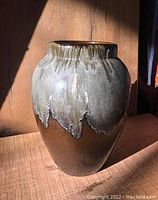 Full view of the large pottery vase showing grey drip glaze over brown body.