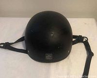 Front view of the black matte beanie motorcycle helmet with visible DOT certification label and chin strap.
