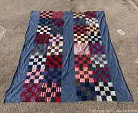 Full view of the patchwork quilt cover laid out on the ground, showing two vertical panels of colorful hand sewn squares with a blue border.