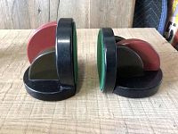 Side view showing the shape and contrasting colors of the two book ends, black and red, each with green felt on base.