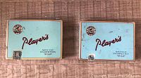 Front view of two Player's Navy Cut Cigarettes Mild metal tins with light blue fronts and hinged lids.