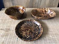 Three Bennington Print pottery items shown from front: two bowls (one round, one rectangular) and one round plate, all with mottled brown and tan glaze pattern.