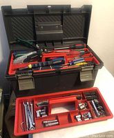 Open Rubbermaid tool tote showing assorted hand tools inside including pliers, screwdrivers, wrenches, and utility knife