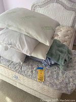 Full view of the bedding items showing the comforter on a mattress with pillows and folded blankets stacked on top.