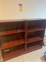 Two wooden book shelves positioned side by side, each with three shelves, dark wood finish, sturdy construction.