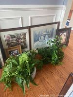 Image showing four framed prints including landscape and baby photo, along with artificial greenery in foreground.