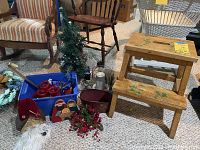 Overall view of wooden painted two-step stool, blue bin with red candles, miniature Christmas tree, Santa decor, and red berry garland on carpeted floor with chairs and other furniture in background.