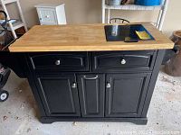 Full front and side view of portable kitchen island showing butcher block top and black granite cutting board.