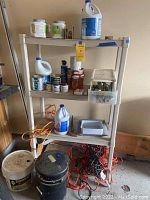Full view of beige Sterilite 4 shelf plastic shelving unit loaded with various painting, cleaning, and hardware supplies.