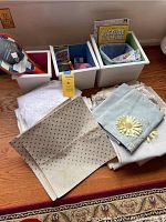 Three storage bins filled with linens, card games, and paddleball set placed on wooden floor against wall