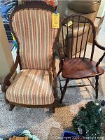 Three assorted chairs shown: one upholstered rocking chair with striped fabric and carved wood, one wooden armchair with spindled rounded back, and a standard wooden chair with flat seat and slatted back seen in the background.