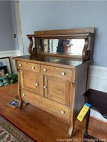 Antique oak dining room hutch with mirror and porcelain knobs shown from side angle