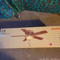 Box with product image and details showing 52 inch flush mount ceiling fan with 5 dark walnut blades and aged-champagne glass bowl light fixture.