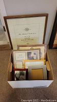 Box containing multiple assorted picture frames stacked inside, showcasing wood and gold-toned frames of multiple sizes including 16x20, 8x10, 5x7, and baby-sized frames.