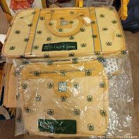 Photo showing both Avon bags, one overnight and one flight bag, still in original packaging showing logo pattern.