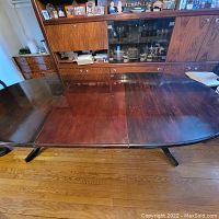 Top view of wood dining table including leaf insert and visible surface scratches.