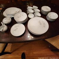 Photo showing whole Harmony House Fine China set with various pieces including plates, bowls, tea cups, creamer, sugar bowl, platter, and serving bowl on table.