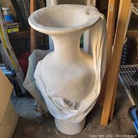 Full view of the ceramic vase showing the flared top and textured surface with draped cloth decoration.