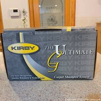 Closed original Kirby box for The Ultimate G Series Carpet Shampoo System, showing branding and product series information.