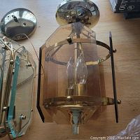 Smoked glass indoor canopy light lying flat on wooden surface showing hexagonal glass panels and central bulb socket.