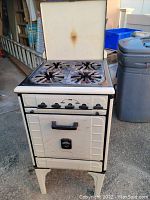 Front view of vintage gas stove with four burners and closed oven door, showing overall appliance condition and details.