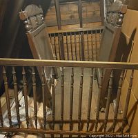 Front view of wood crib with steel frame, showing spindled side rails and wood panels, inside a box or storage area.