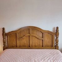 Front view of the solid wood headboard showing arched paneling and turned posts.