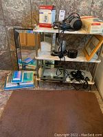 3-tier marbled shelf with mirror, assorted bathroom and personal care items including electric clippers, shaver, scale, alarm clocks, and framed art.