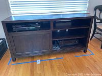 Wood entertainment cabinet with several shelves, sliding door on lower left side, holding Sony audio equipment units.