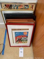 Lot of seven small framed art pieces stacked together, showing variety of frame colors and styles including red, wood, black, and gold tones.
