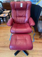 Front view of maroon leather chair with matching ottoman on hardwood floor