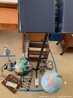 Complete overview of lot including black metal adjustable stand, two large globes, two Oxford dictionary volumes, adjustable book light, wooden soroban abacus and other desktop stands